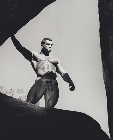 An original gelatin silver print by Jim French depicting the model Jake Tanner, a muscular white male with brown hair, posing nude in the center of a rock formation.